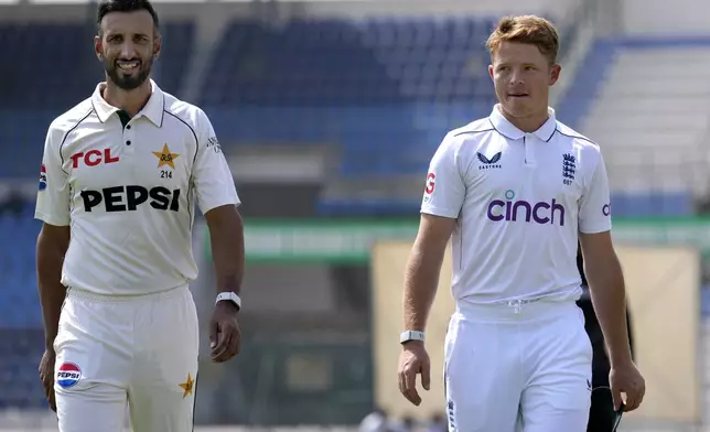 Pakistan's test team skipper Shan Masood, left, and his England's counterpart Ollie Pope pose arrive for a photo shoot with test series trophy, in Multan, Pakistan, Sunday, Oct. 6, 2024. (AP Photo/Anjum Naveed)