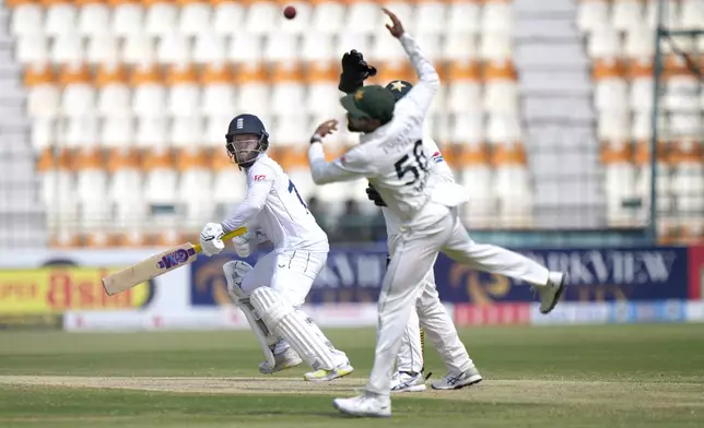 England's Ben Duckett, left, plays a shot as Pakistan's Babar Azam attempts to catch the ball during the third day of the first test cricket match between Pakistan and England, in Multan, Pakistan, Wednesday, Oct. 9, 2024. (AP Photo/Anjum Naveed)