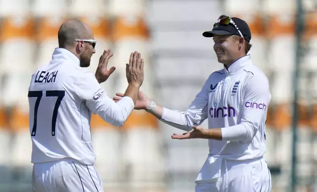 England's Jack Leach, left, celebrates with Ollie Pope after taking the wicket of Pakistan's Shaheen Shah Afridi during the fifth day of the first test cricket match between Pakistan and England, in Multan, Pakistan, Friday, Oct. 11, 2024. (AP Photo/Anjum Naveed)