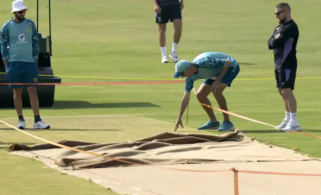 Pakistan's test team's head coach Jason Gillespie, center right, examines the pitch preparing for 1st test cricket match between England and Pakistan, as England's coach Brendon McCullum, right, watch, before a practice session, in Multan, Pakistan, Sunday, Oct. 6, 2024. (AP Photo/Anjum Naveed)