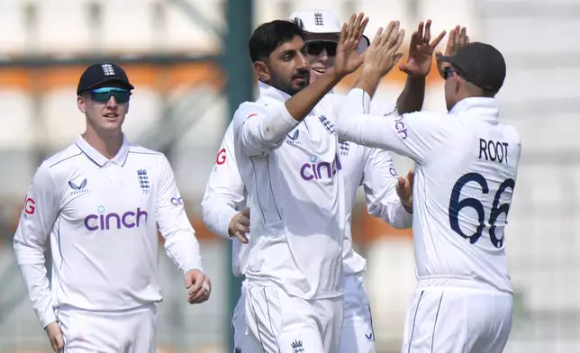 England's Shoaib Bashir, center, celebrates with teammates after taking the wicket of Pakistan's Saud Shakeel during the second day of the first test cricket match between Pakistan and England, in Multan, Pakistan, Tuesday, Oct. 8, 2024. (AP Photo/Anjum Naveed)