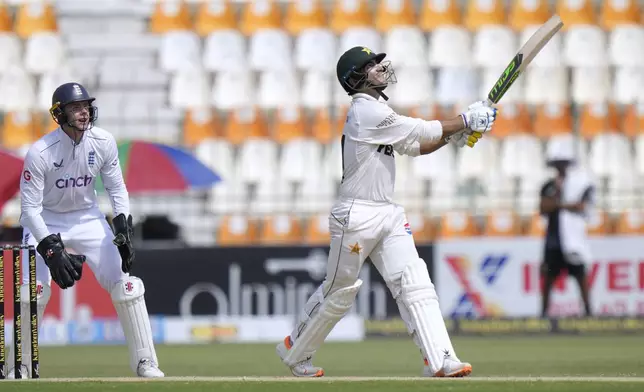 Pakistan's Naseem Shah, right, follows the ball after playing a shot for six as England's Jamie Smith watches during the second day of the first test cricket match between Pakistan and England, in Multan, Pakistan, Tuesday, Oct. 8, 2024. (AP Photo/Anjum Naveed)