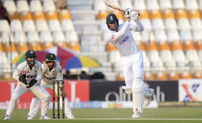 England's Zak Crawley, right, plays a shot as Pakistan's Mohammad Rizwan, left, and Salman Ali Agha watch during the second day of the first test cricket match between Pakistan and England, in Multan, Pakistan, Tuesday, Oct. 8, 2024. (AP Photo/Anjum Naveed)