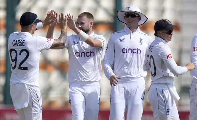 England's Gus Atkinson, second left, celebrates with teammates after taking the wicket of Pakistan's Saim Ayub during the first day of the first test cricket match between Pakistan and England, in Multan, Pakistan, Monday, Oct. 7, 2024. (AP Photo/Anjum Naveed)