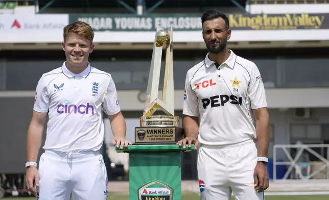 Pakistan's test team skipper Shan Masood, right, and his England's counterpart Ollie Pope pose for photograph with test series trophy, in Multan, Pakistan, Sunday, Oct. 6, 2024. (AP Photo/Anjum Naveed)