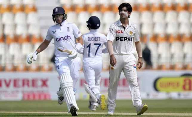 England's Joe Root, left, and Ben Duckett, center, run between the wickets as Pakistan's Naseem Shah watches during the third day of the first test cricket match between Pakistan and England, in Multan, Pakistan, Wednesday, Oct. 9, 2024. (AP Photo/Anjum Naveed)