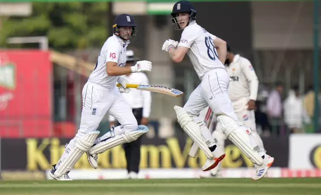 England's Joe Root, left, and Harry Brook run between the wicket during the third day of the first test cricket match between Pakistan and England, in Multan, Pakistan, Wednesday, Oct. 9, 2024. (AP Photo/Anjum Naveed)