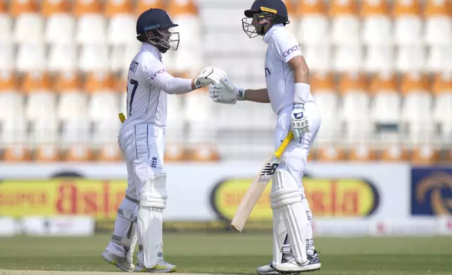 England's Ben Duckett, left, and Joe Root bumps their fists to celebrate their hundred runs partnership during the third day of the first test cricket match between Pakistan and England, in Multan, Pakistan, Wednesday, Oct. 9, 2024. (AP Photo/Anjum Naveed)