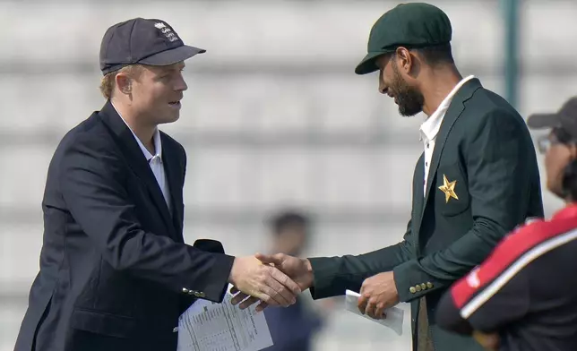 Pakistan's Shan Masood, right, shakes hand with England's Ollie Pope after coin toss before the start of the play of first test cricket match between Pakistan and England, in Multan, Pakistan, Monday, Oct. 7, 2024. (AP Photo/Anjum Naveed)