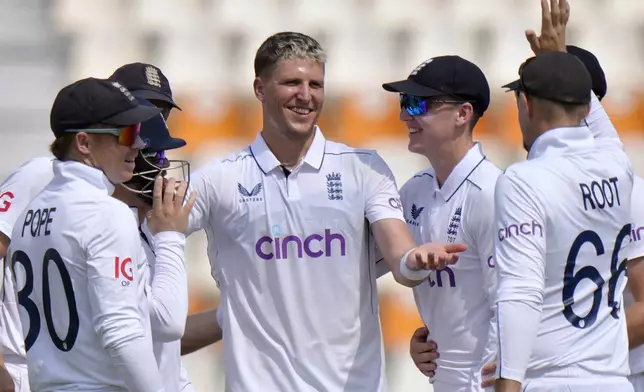 England's Brydon Carse, center, celebrates with teammates after taking the wicket of Pakistan's Naseem Shah during the second day of the first test cricket match between Pakistan and England, in Multan, Pakistan, Tuesday, Oct. 8, 2024. (AP Photo/Anjum Naveed)