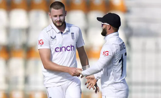 England's Gus Atkinson, left, celebrates with teammate after taking the wicket of Pakistan's Abdullah Shafique during the first day of the first test cricket match between Pakistan and England, in Multan, Pakistan, Monday, Oct. 7, 2024. (AP Photo/Anjum Naveed)