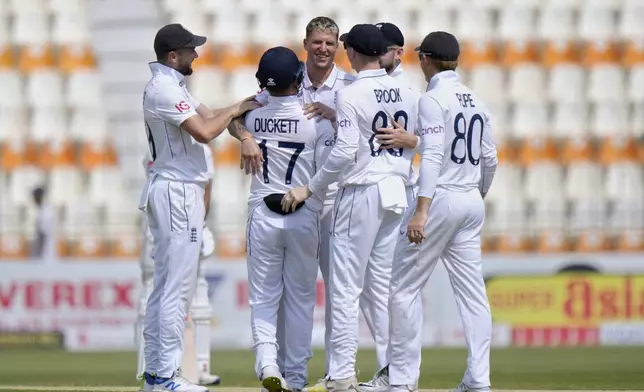 England's Brydon Carse, center, celebrates with teammates after taking the wicket of Pakistan's Naseem Shah during the second day of the first test cricket match between Pakistan and England, in Multan, Pakistan, Tuesday, Oct. 8, 2024. (AP Photo/Anjum Naveed)