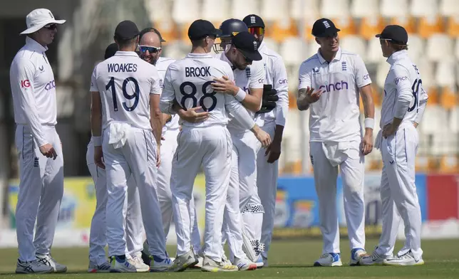 England's Jack Leach, center in glasses, celebrates with teammates after taking the wicket of Pakistan's Salman Ali Agha during the fifth day of the first test cricket match between Pakistan and England, in Multan, Pakistan, Friday, Oct. 11, 2024. (AP Photo/Anjum Naveed)