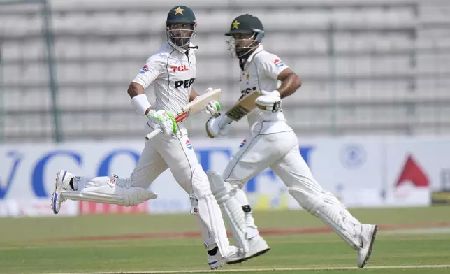 Pakistan's Shan Masood, left, and Abdullah Shafique run between during the first day of the first test cricket match between Pakistan and England, in Multan, Pakistan, Monday, Oct. 7, 2024. (AP Photo/Anjum Naveed)