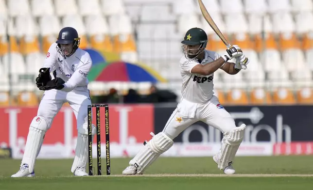 Pakistan's Abdullah Shafique, right, plays a shot as England's Jamie Smith watches during the first day of the first test cricket match between Pakistan and England, in Multan, Pakistan, Monday, Oct. 7, 2024. (AP Photo/Anjum Naveed)