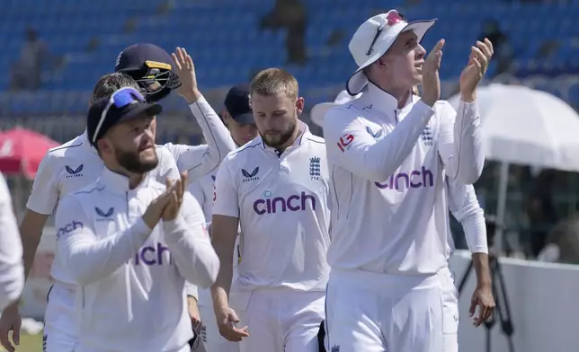 England's Zak Crawley, right, and teammates acknowledge crowd as they walk off the field after winning the first test cricket match against Pakistan, in Multan, Pakistan, Friday, Oct. 11, 2024. (AP Photo/Anjum Naveed)