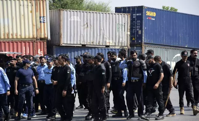 Police officers assemble next to shipping containers placed by authorities to block a road leading to important government buildings in an attempt to prevent supporters of imprisoned former Prime Minister Imran Khan from holding a rally seeking his release in Islamabad, Pakistan, Friday, Oct. 4, 2024.(AP Photo/W.K. Yousafzai)