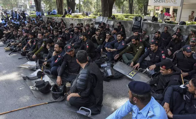 Police officers assemble next to shipping containers placed by authorities to block a road leading to important government buildings in an attempt to prevent supporters of imprisoned former Prime Minister Imran Khan from holding a rally seeking his release in Islamabad, Pakistan, Friday, Oct. 4, 2024. (AP Photo/W.K. Yousafzai)