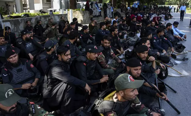 Police officers assemble next to shipping containers placed by authorities to block a road leading to important government buildings in an attempt to prevent supporters of imprisoned former Prime Minister Imran Khan from holding a rally seeking his release in Islamabad, Pakistan, Friday, Oct. 4, 2024. (AP Photo/W.K. Yousafzai)