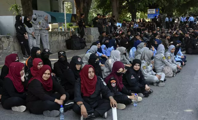 Police officers assemble next to shipping containers placed by authorities to block a road leading to important government buildings in an attempt to prevent supporters of imprisoned former Prime Minister Imran Khan from holding a rally seeking his release in Islamabad, Pakistan, Friday, Oct. 4, 2024. (AP Photo/W.K. Yousafzai)