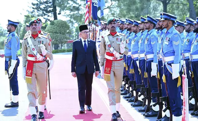 In this photo released by Pakistan's Prime Minister Office, Malaysian Prime Minister Anwar Ibrahim, center, reviews guard of honor at the Prime Minister House in Islamabad, Pakistan, Thursday, Oct. 3, 2024. (Prime Minister Office via AP)