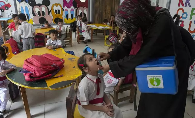 A health worker administers a polio vaccine to a child in a school, in Karachi, Pakistan, Monday, Oct. 28, 2024. (AP Photo/Fareed Khan)