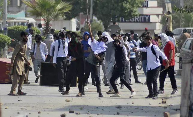 Students throw stones toward police during clashes as they protest over an alleged on-campus rape in Punjab, in Rawalpindi, Pakistan, Thursday, Oct. 17, 2024. (AP Photo/W.K. Yousafzai)