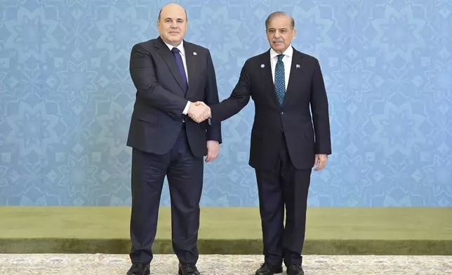 In this photo released by the Press Information Department, Russian Prime Minister Mikhail Mishustin, left, shakes hand with his Pakistani counterpart Shehbaz Sharif as he arrives to attend Shanghai Cooperation Organization (SCO) meeting, in Islamabad, Pakistan, Wednesday, Oct. 16, 2024. (Press Information Department via AP)