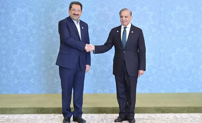 In this photo released by the Press Information Department, Iranian Minister for Industry, Trade and Mining Seyed Mohammad Atabak, left, shakes hand with Pakistani Prime Minister Shehbaz Sharif as he arrives to attend Shanghai Cooperation Organization (SCO) meeting, in Islamabad, Pakistan, Wednesday, Oct. 16, 2024. (Press Information Department via AP)