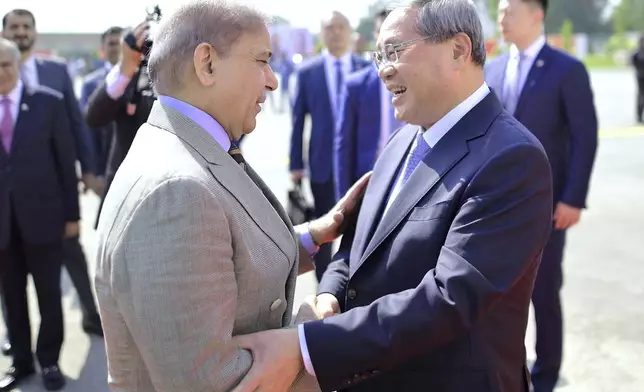 In this photo released by the Press Information Department, China's Premier Li Qiang, right, greets Pakistan's Prime Minister Shehbaz Sharif, upon his arrival at an airbase in Rawalpindi, Pakistan, Monday, Oct. 14, 2024. (Press Information Department via AP)