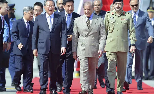 In this photo released by the Press Information Department, China's Premier Li Qiang, third left, walks Pakistan's Prime Minister Shehbaz Sharif, third right, upon his arrival at an airbase in Rawalpindi, Pakistan, Monday, Oct. 14, 2024. (Press Information Department via AP)