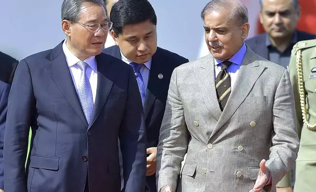 In this photo released by the Press Information Department, China's Premier Li Qiang, left, walks Pakistan's Prime Minister Shehbaz Sharif, upon his arrival at an airbase in Rawalpindi, Pakistan, Monday, Oct. 14, 2024. (Press Information Department via AP)