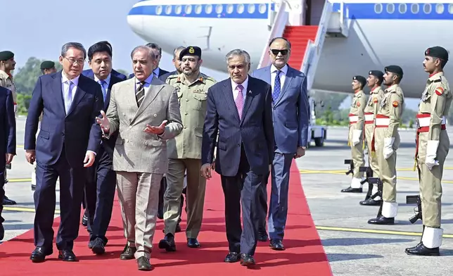 In this photo released by the Press Information Department, China's Premier Li Qiang, left, walks Pakistan's Prime Minister Shehbaz Sharif, second left, upon his arrival at an airbase in Rawalpindi, Pakistan, Monday, Oct. 14, 2024. (Press Information Department via AP)