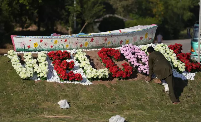 A worker gives the final touches to a floral artwork "welcome" display close to the venue of the upcoming Shanghai Cooperation Organization (SCO) summit in Islamabad, Pakistan, Sunday, Oct. 13, 2024. (AP Photo/Anjum Naveed)