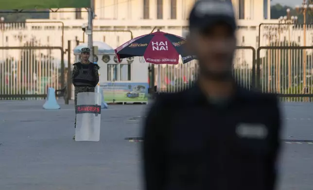 A police officer and a paramilitary soldier stand guard at a barricaded road leading to Presidency, in background, and to the venue of the upcoming Shanghai Cooperation Organization (SCO) summit in Islamabad, Pakistan, Sunday, Oct. 13, 2024. (AP Photo/Anjum Naveed)