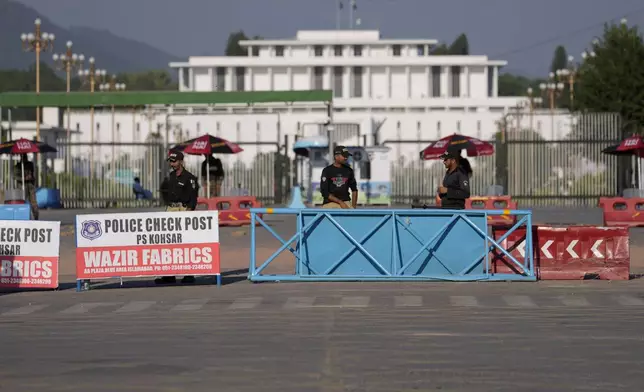 Police officers stand guard at a barricaded road leading to Presidency, in background, and to the venue of the upcoming Shanghai Cooperation Organization (SCO) summit in Islamabad, Pakistan, Sunday, Oct. 13, 2024. (AP Photo/Anjum Naveed)