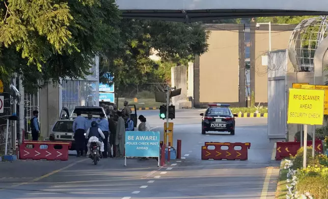 Police officer frisk a car at a checkpoint close to the venue of the upcoming Shanghai Cooperation Organization (SCO) summit in Islamabad, Pakistan, Sunday, Oct. 13, 2024. (AP Photo/Anjum Naveed)