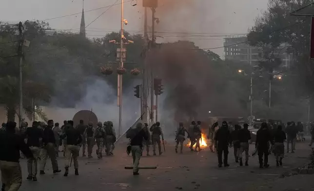 Police and paramilitary soldiers chase supporters of the Tehreek-e-Labbaik Pakistan party during clashes in Karachi, Pakistan, Sunday, Oct. 13, 2024. (AP Photo/Fareed Khan)