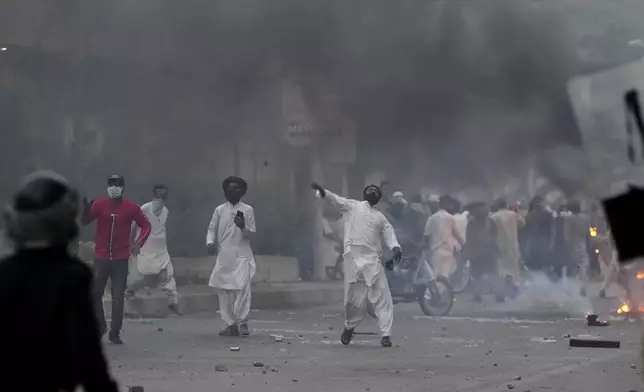 Supporters of the Tehreek-e-Labbaik Pakistan party burn bushes and throw stone towards police during clashes in Karachi, Pakistan, Sunday, Oct. 13, 2024. (AP Photo/Fareed Khan)