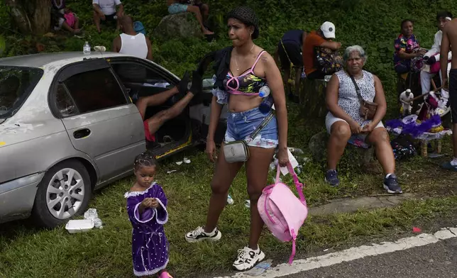 Pilgrims rest on the side of the road after leaving San Felipe Church to honor the Black Christ in Portobelo, Panama, Monday, Oct. 21, 2024, during a festival celebrating the iconic statue that was found on the shore in 1658. (AP Photo/Matias Delacroix)