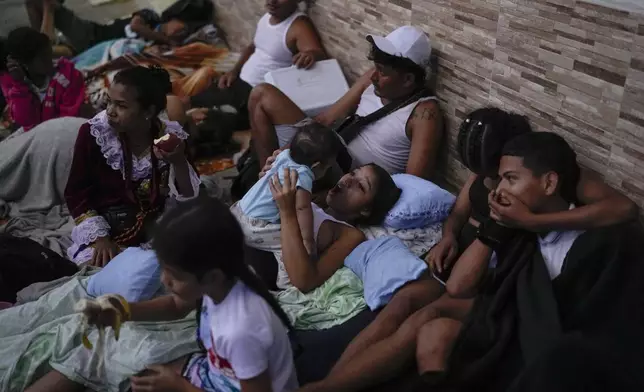 Pilgrims rest outside San Felipe Church where they came to honor the Black Christ in Portobelo, Panama, early Monday, Oct. 21, 2024, during a festival celebrating the iconic statue that was found on the shore in 1658. (AP Photo/Matias Delacroix)