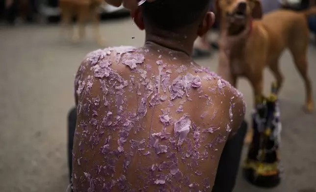 A woman drips candle wax on Valentin Solis as part of his penance, as pilgrims make their way, some crawling, to the San Felipe Church in Portobelo, Panama, Monday, Oct. 21, 2024, during a festival celebrating the iconic Black Christ statue that was found on the shore in 1658. (AP Photo/Matias Delacroix)