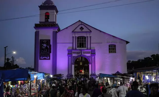 Pilgrims arrive at San Felipe Church to honor the Black Christ in Portobelo, Panama, at dawn Monday, Oct. 21, 2024, during a festival celebrating the iconic statue that was found on the shore in 1658. (AP Photo/Matias Delacroix)