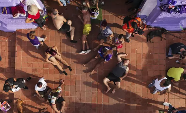 Pilgrims rest from crawling to San Felipe Church to honor the Black Christ in Portobelo, Panama, early Monday, Oct. 21, 2024, during a festival celebrating the iconic statue that was found on the shore in 1658. (AP Photo/Matias Delacroix)