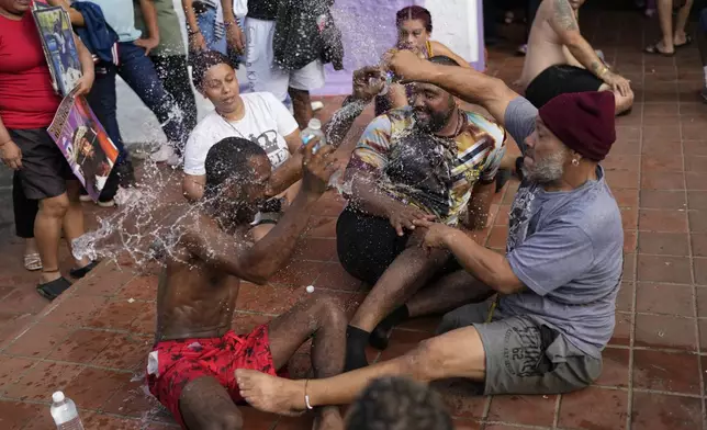 Pilgrims joke around with water after crawling to San Felipe Church to honor the Black Christ in Portobelo, Panama, Monday, Oct. 21, 2024, during a festival celebrating the iconic statue that was found on the shore in 1658. (AP Photo/Matias Delacroix)