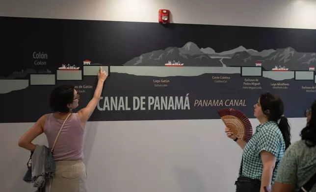 Tourists look at a mural explaining how the Panama Canal works at the Miraflores Locks in Panama City, Monday, Sept. 2, 2024. (AP Photo/Matias Delacroix)