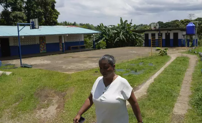 La Represa School Principal Zuleyka Ramirez walks through a yard in the school, which closes when the water supply is cut off, in Colon, Panama, Monday, Sept. 2, 2024. Under a proposed plan to dam the nearby Indio River and secure the Panama Canal's uninterrupted operation, the community could gain more reliable access to water. (AP Photo/Matias Delacroix)