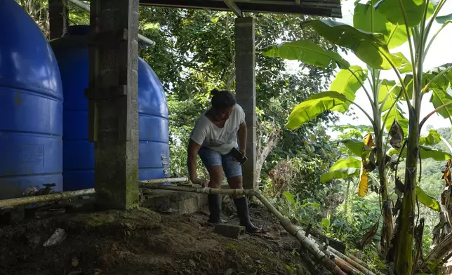 Ilda Rodriguez turns on a faucet to distribute water to La Represa neighborhood in Colon, Panama, Monday, Sept. 2, 2024. Under a proposed plan to dam the nearby Indio River and secure the Panama Canal's uninterrupted operation, the community would gain more reliable access to water. (AP Photo/Matias Delacroix)