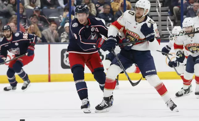 Columbus Blue Jackets' Zach Werenski, left, and Florida Panthers' A.J. Greer chase the puck during the first period of an NHL hockey game Tuesday, Oct. 15, 2024, in Columbus, Ohio. (AP Photo/Jay LaPrete)