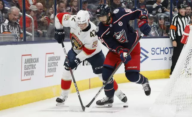 Florida Panthers' Gustav Forsling, left, and Columbus Blue Jackets' Kirill Marchenko fight for the puck during the second period of an NHL hockey game Tuesday, Oct. 15, 2024, in Columbus, Ohio. (AP Photo/Jay LaPrete)